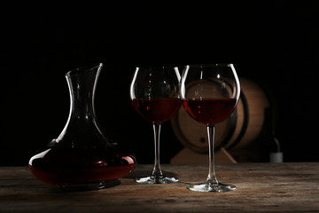 Elegant decanter and glasses with red wine on table against dark background
