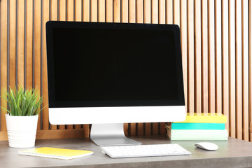 Computer with blank monitor at table indoors. Mock up for design