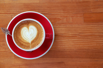Cup of fresh aromatic coffee on wooden table, top view