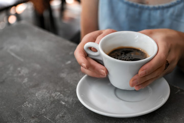 Woman with cup of fresh aromatic coffee at table, closeup