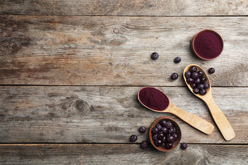 Flat lay composition with acai powder and berries on wooden background