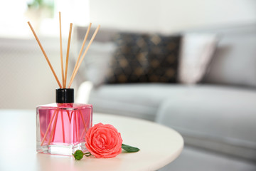 Obraz na płótnie Canvas Aromatic reed air freshener and rose on table indoors