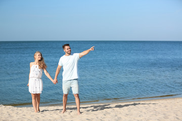 Fototapeta na wymiar Happy young couple holding hands at beach on sunny day