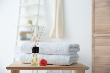 Reed air freshener and stack of towels on table against blurred background