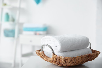 Wicker tray with towels on table against blurred background