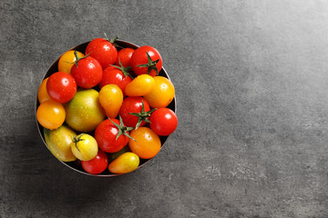 Bowl with tasty juicy tomatoes and space for text on grey background, top view