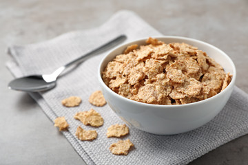 Bowl with cornflakes on gray table. Whole grain cereal for breakfast