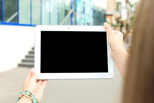 Woman holding tablet with blank screen outdoors. Mockup for design