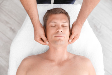 Relaxed man receiving head massage in wellness center, top view