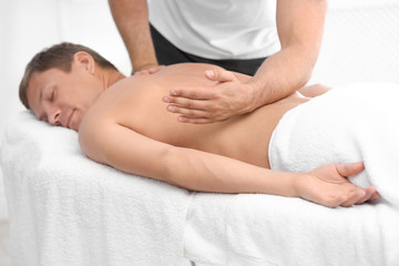 Fototapeta na wymiar Relaxed man receiving back massage in wellness center
