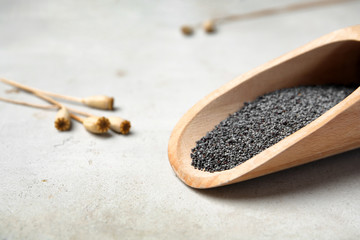 Wooden scoop with poppy seeds on table, closeup