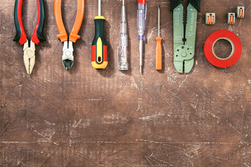 Different electrical tools on brown wooden background with place for text, top view.