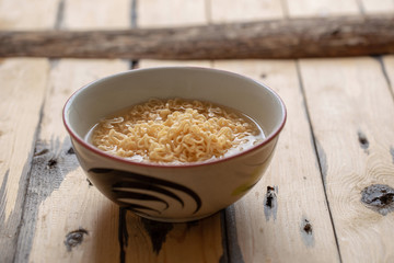 Noodles in bowl on wooden background, selective focus