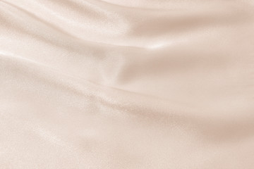 The texture of the satin fabric of beige color for the background