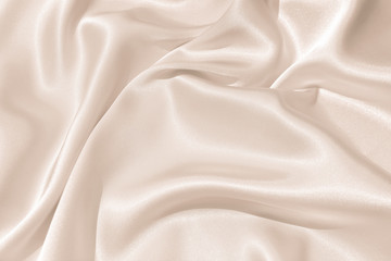 The texture of the satin fabric of beige color for the background