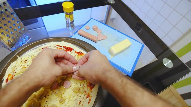 POV Person Add Hot-dog Slices On To Pizza 4K. Person Point Of View Of Person's Hands Holding Hot Dog Slices In Focus And Spreading All Over The Pizza In Making.