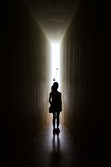 Young girl in dark room walking to the light