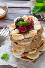 Pancakes with bananas, fresh honey and raspberries. Decorated with a sprig of mint.