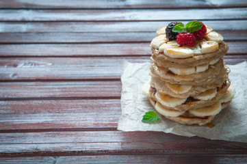 Pancakes with bananas, fresh honey and raspberries. Decorated with a sprig of mint.