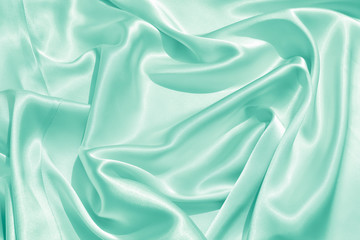 The texture of the satin fabric of green color for the background 