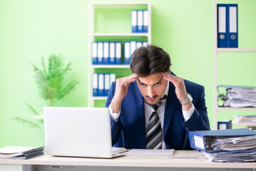Businessman unhappy with excessive work sitting in the office 