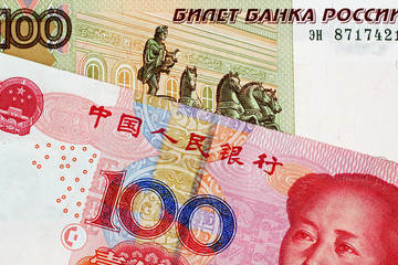 A close up image of a 100 Chinese yuan bank note with a 100 Russian ruble bank note 