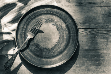 Obraz na płótnie Canvas Empty clay plate with a fork on an old wooden table, top view, copy space