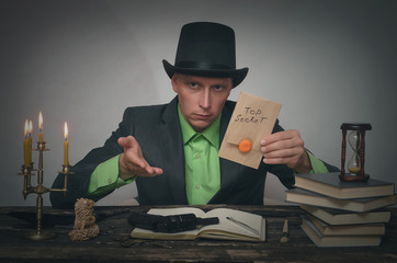 Man in bowler with top secret documents in hands is sitting by table. Detective or spy agent or police inspector concept.