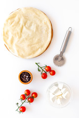 Process of cooking pizza. Pizza Margarita. Raw dough and filling. Cherry tomatoes, cheese mozzarella, spices near knife for pizza on white background top view mockup