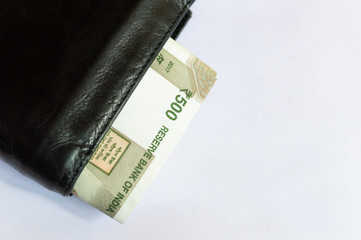 Indian currency notes Rs 500 in a black leather wallet on a white background top view