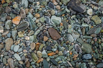 Multi-coloured pebbles rounded along the bank of a river stream in Kashmir
