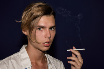 A young guy smokes a cigarette. Bad habits. 