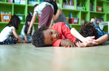 A stubborn intractable and naughty boy kids in classroom at kindergarten pre school anti learning...