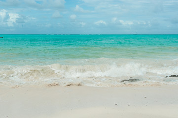 Small waves from a storm in the Indian ocean. Clean water runs on the light sand of the beach