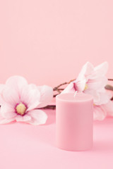 Delicate flower scented candle over the pastel pink background with copy space