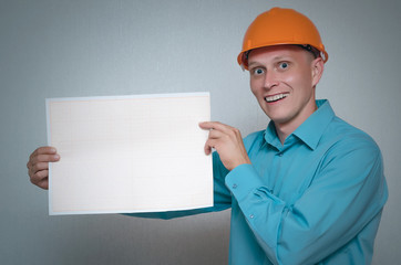Happy builder construction worker is holding in hand a plan draft document isolated on gray background.