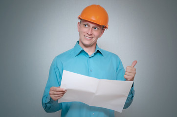 Happy builder construction worker is holding in hand a plan draft document isolated on gray background.