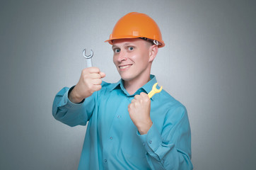 Happy builder worker with wrench tool in hands isolated on gray background.