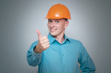 Happy builder worker is showing a thumbs up isolated on gray background.