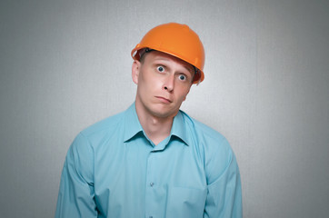 Perplexed builder worker isolated on gray background.