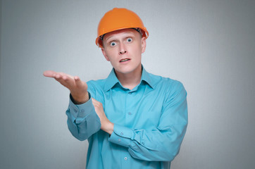 Perplexed builder worker isolated on gray background.