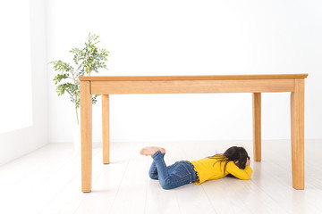 机の下に避難する子ども