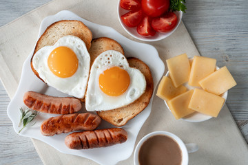 Breakfast with love - fried eggs in the shape of a heart, fried sausages and coffee