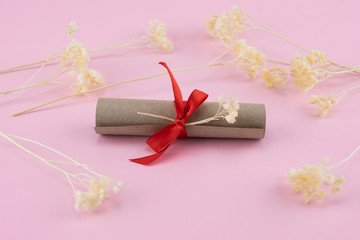 Scroll decorate with white dried flowers on pastel pink background