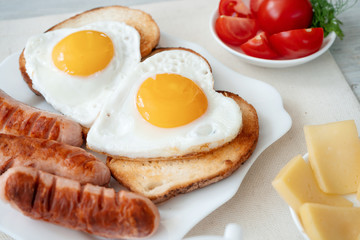 Breakfast with love - fried eggs in the shape of a heart, fried sausages and coffee