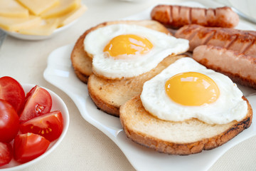 Breakfast with love - fried eggs in the shape of a heart, fried sausages and coffee