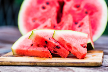 Slices and half of fresh watermelon on wooden board