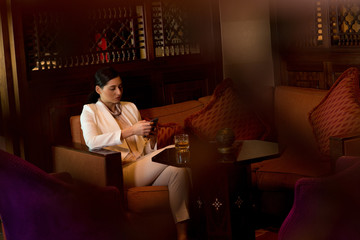 Expat woman messaging on mobile at restaurant.