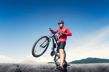 Young man riding mountain bike on the background of mountains at blue sky