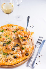 Delicious cheese string slice lifted of full supreme pizza baked fresh out of the oven on a white background with prawns, cheese and black olives